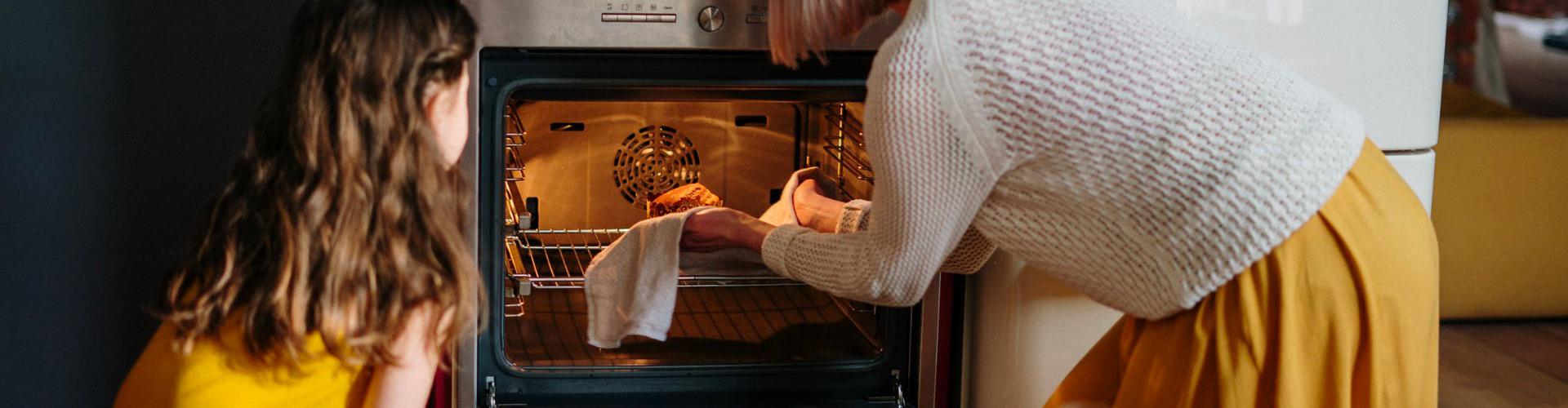 photo of a grandparent and child cooking using the oven